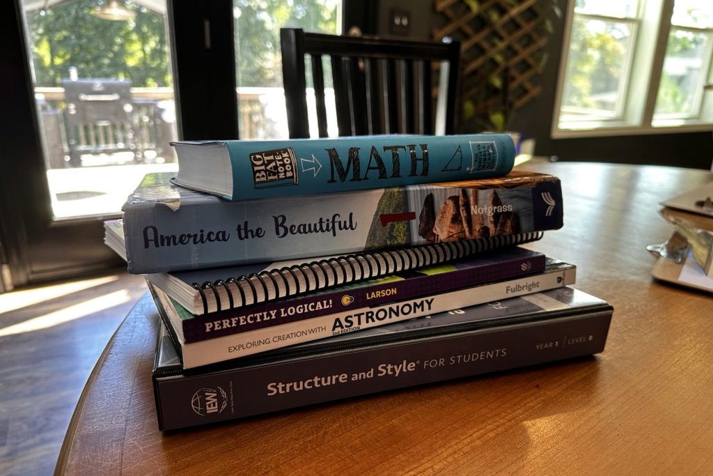Stack of middle school homeschool curriculum books on a dining room table